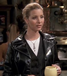 a woman holding a coffee cup in her right hand and wearing a black leather jacket