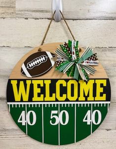 a welcome sign hanging on the side of a wooden wall with footballs and bows