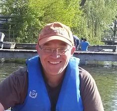 a man in a life jacket is smiling for the camera while sitting on a boat