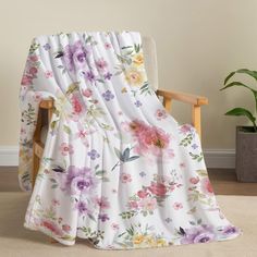 a chair with a flowered blanket on it in front of a potted plant