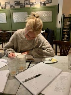 a woman sitting at a table writing in a notebook