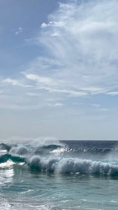 two surfers are riding the waves on their surfboards in the ocean under a blue sky with wispy clouds