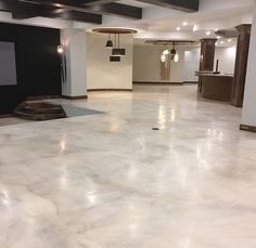 an empty room with white marble flooring and black ceiling lights hanging from the ceiling