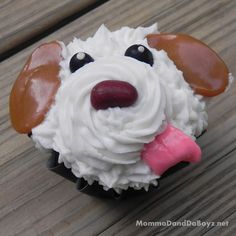 a cupcake shaped like a dog with icing on it's face and tongue