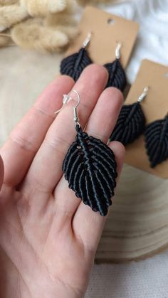 a person holding some kind of black earrings in their hand and it looks like they are made out of yarn