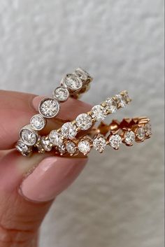 a woman's hand holding two gold and white diamond wedding rings in her left hand