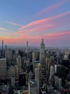 an aerial view of the city at sunset with pink and blue clouds in the sky