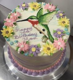 a hummingbird birthday cake decorated with flowers