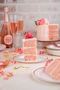 a slice of strawberry cake sitting on top of a white plate next to two wine glasses