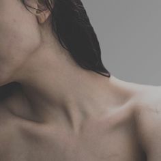 the back of a woman's head and neck with no shirt on, against a gray background