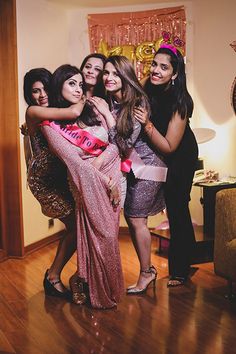 four women pose for the camera in their evening gowns and tiaras at a bachelor party