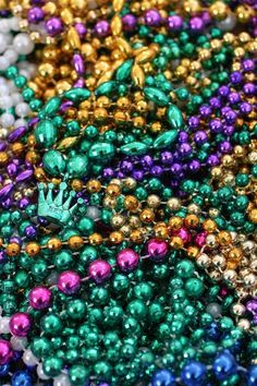 many different colored beads with a green crown on top, and one has a small white hand in the middle