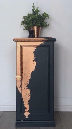 a black and gold cabinet with a potted plant sitting on it's top