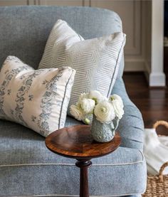 a blue couch with some white flowers on top of it and a basket next to it