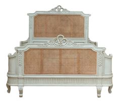 a white bed with wicker headboard and foot board on top of the frame