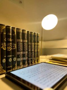 there are many books lined up on the table with an electronic device in front of them