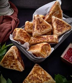 several pieces of pizza sitting on top of a tray next to sauces and napkins