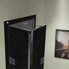 a black cabinet sitting in the corner of a room next to a wall with pictures on it