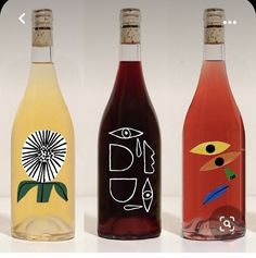 three wine bottles with different designs on them