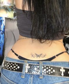 the back of a woman's stomach with a cross tattoo on her left side