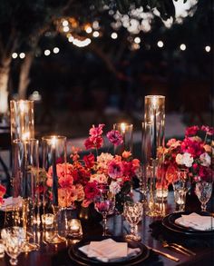 the table is set with candles, flowers and glass vases for an elegant dinner