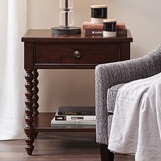 a small table with a lamp on top of it next to a chair and window