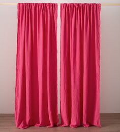 two pink curtains hanging on a white wall