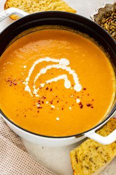 a bowl of carrot soup with crackers on the side