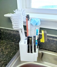 toothbrushes and brushes are in a holder on the sink