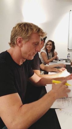 a group of people sitting at a table with papers and pens in front of them