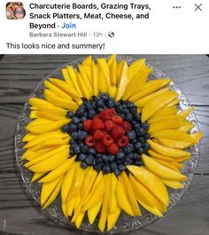 a sunflower made out of bananas, raspberries and blueberries on a plate