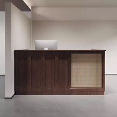 an empty room with a wooden desk and white walls