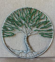 a metal wire tree with green beads in the shape of a circle on a beige background