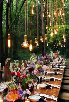 a long wooden table with lots of flowers and lights hanging from it