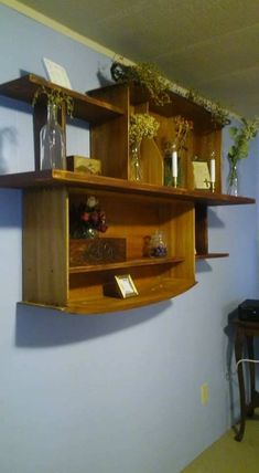 a wooden shelf filled with vases and other items on top of a blue wall