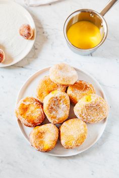 powdered sugar covered donuts on a plate next to a cup of tea