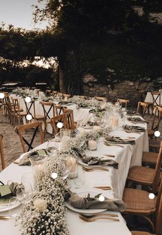 a long table is set up with white linens and candles for an elegant dinner