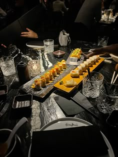 a table topped with lots of food on top of a black table covered in plates and glasses