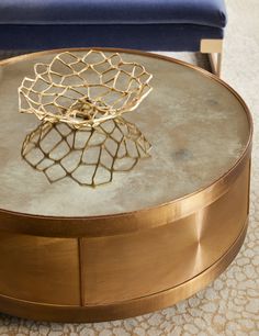 a coffee table with a metal structure on top and a blue chair in the background