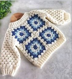 a blue and white crocheted sweater sitting on top of a table