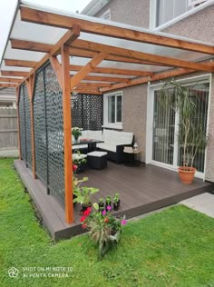 an outdoor patio with wooden pergols and plants on the grass in front of it