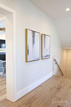 an empty room with two paintings on the wall and a staircase leading up to it