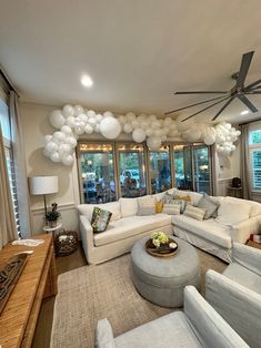 a living room filled with lots of furniture and balloons hanging from the ceiling above it