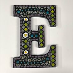 the letter e is made out of stained glass and has flowers on it's sides