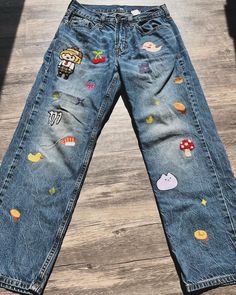 an old pair of jeans with patches on them sitting on the floor in front of a wooden floor