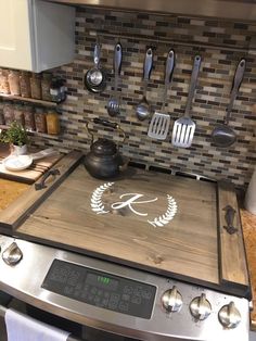 a stove top oven sitting inside of a kitchen next to a counter with utensils on it