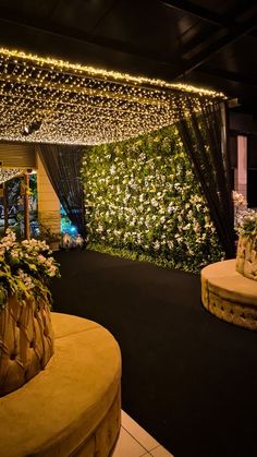 an outdoor area with flowers and lights on the ceiling, surrounded by greenery at night