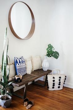 a wooden bench sitting on top of a hard wood floor next to a potted plant