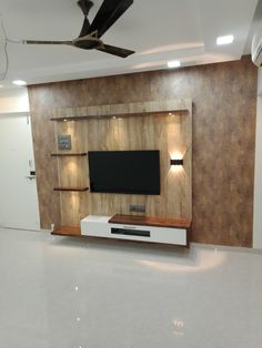 an empty living room with a flat screen tv on the wall and ceiling fan above it