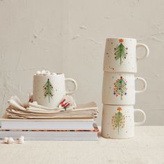 three coffee mugs sitting next to each other on top of a stack of books